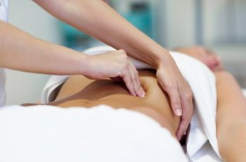 Esteticista fazendo massagem num corpo de mulher, como na clínica Teresa Noviello